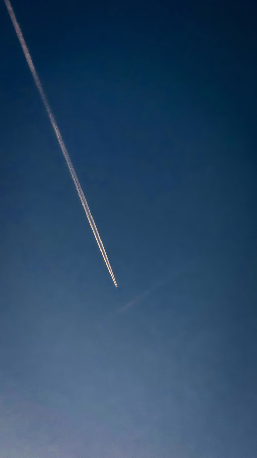 Aircraft Contrail Streaking Across Clear Blue Sky in Minimalist Composition