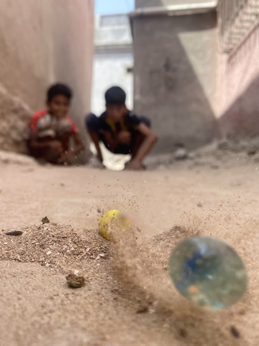 Children Playing in a Narrow Alley Amid Dusty Ground and Urban, Blurry Background