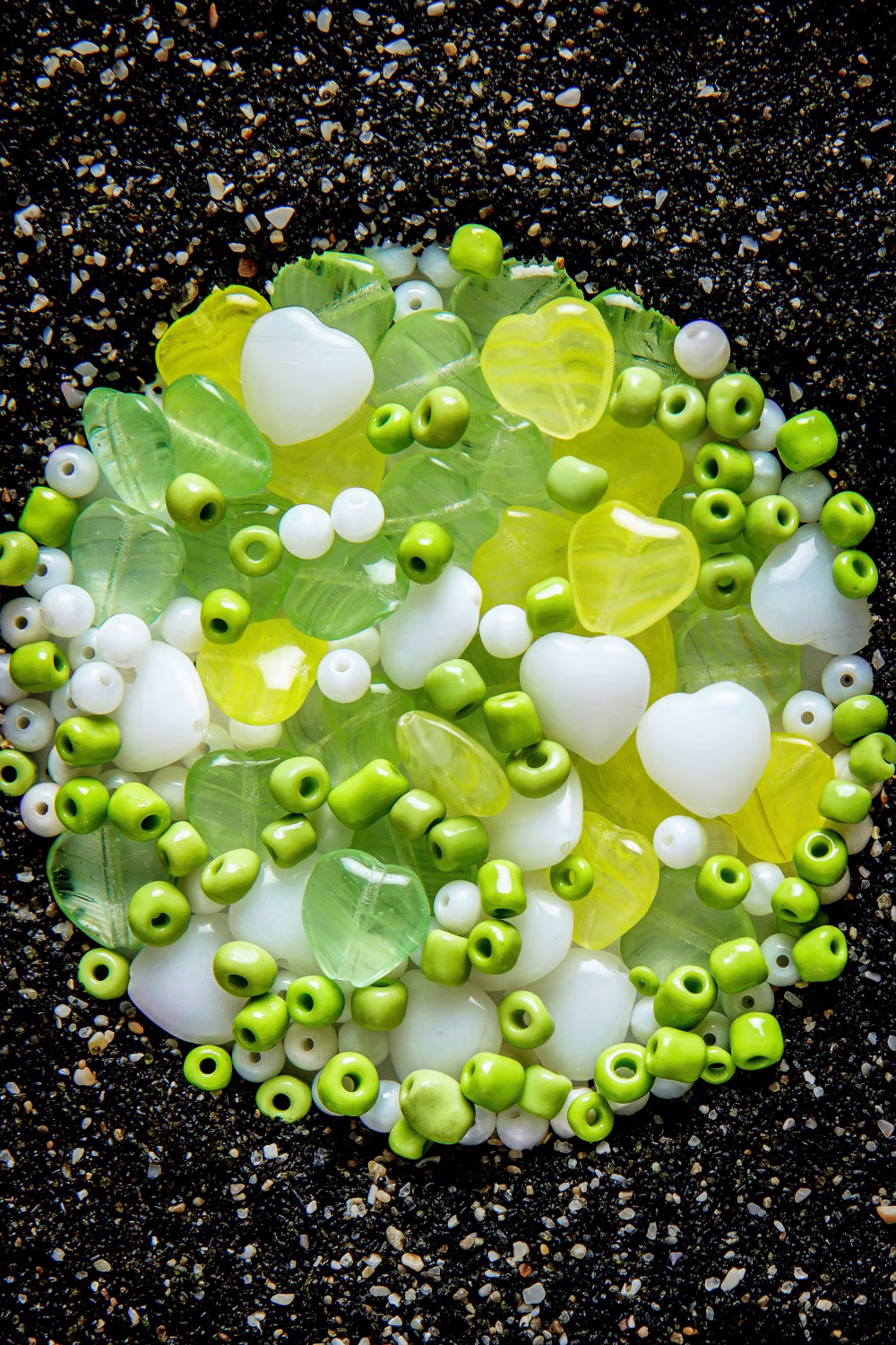 Colorful Assorted Beads on Black Sand Background for Artistic Creations