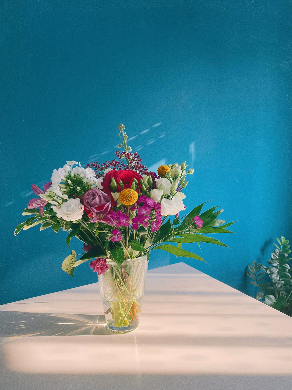 Colorful Floral Bouquet in Glass Vase Against Blue Artistic Background