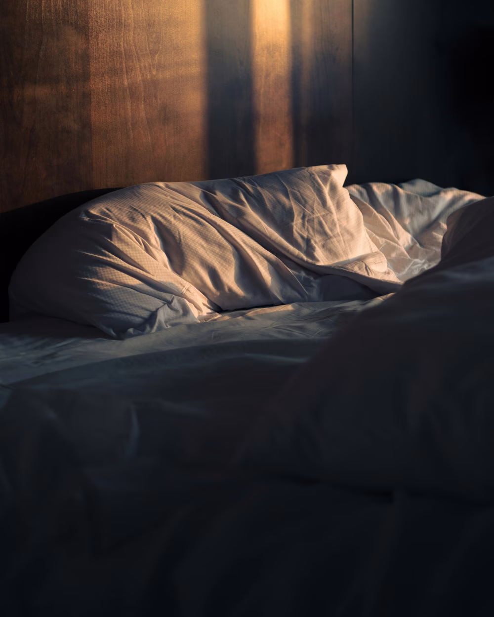 Cozy Morning Sunlight Illuminating Rumpled White Bed Linens in a Bedroom