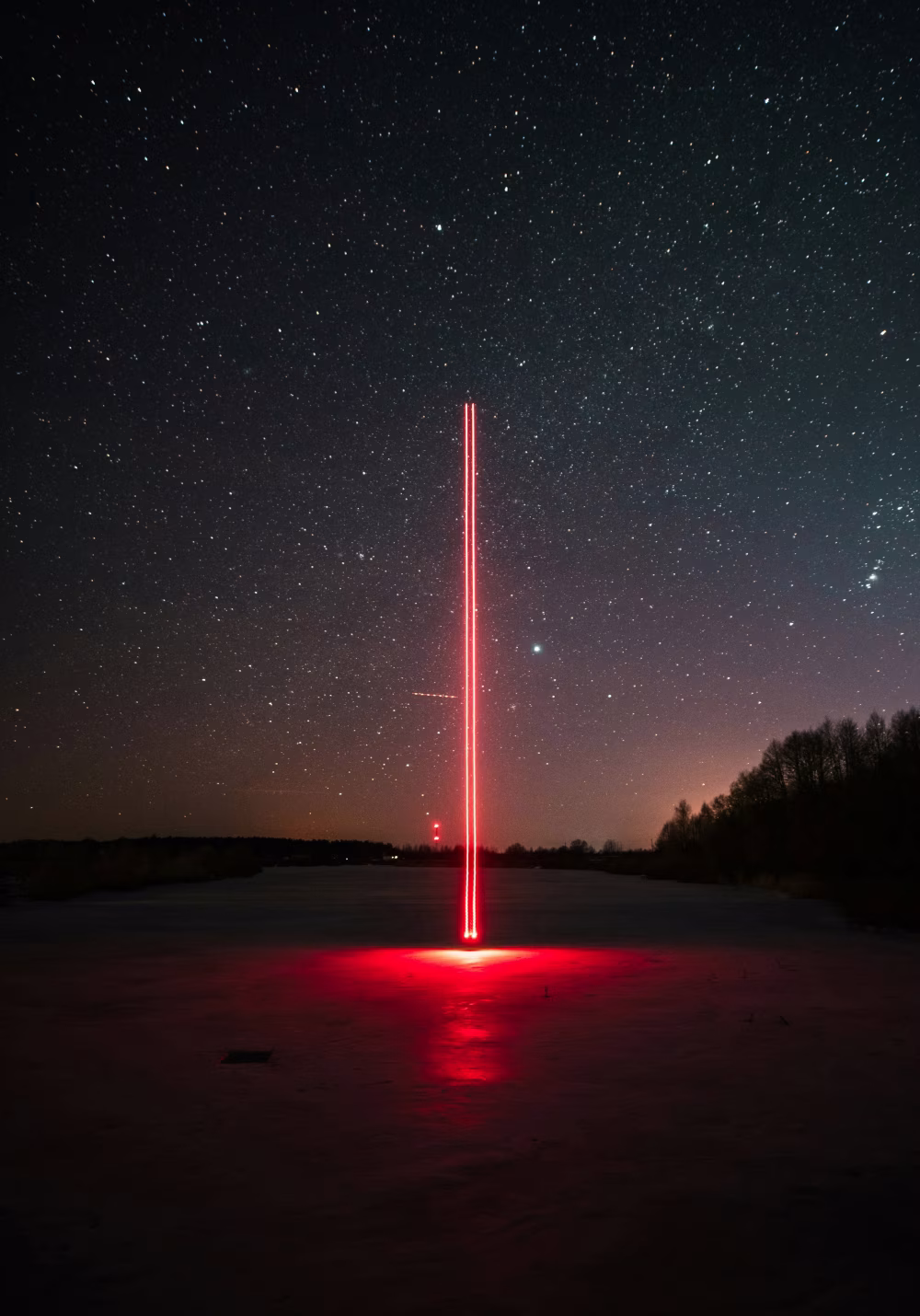 Glowing Red Light Beam Under Starry Night Sky in a Remote Landscape