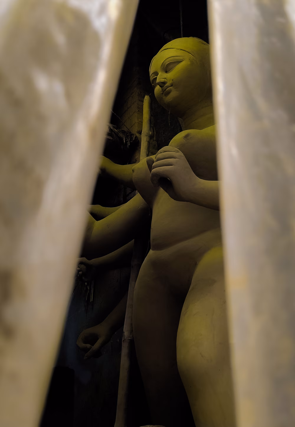 Golden Buddha Statue Hidden Between Curtains in Dim Temple Corner, Serene Silhouette