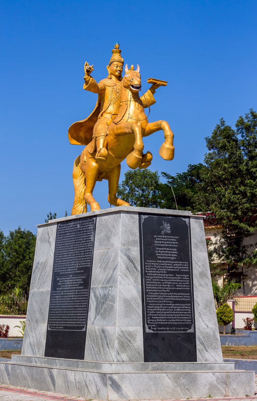 Golden Horse Statue On Marble Pedestal Monument Under Clear Blue Sky With Trees In Background