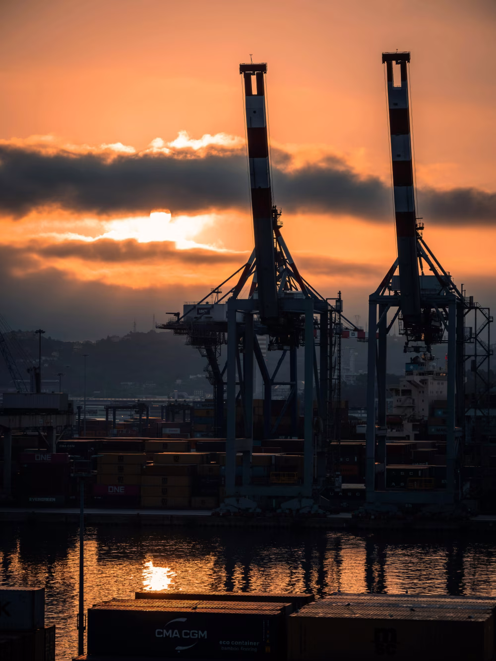 Industrial Port at Sunset With Crane Silhouettes and Cargo Containers by the Water