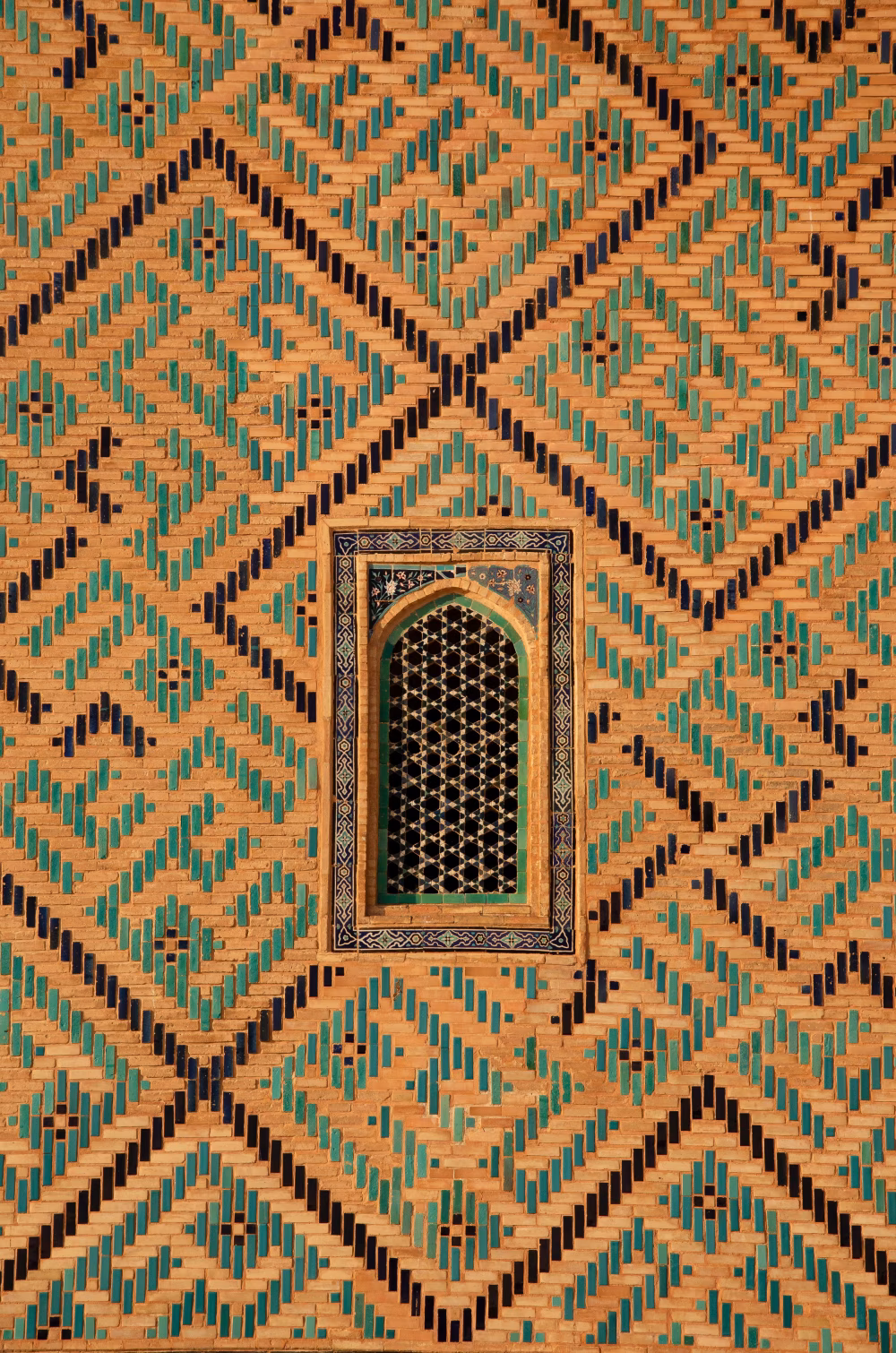 Ornate Geometric Mosaic Wall with a Decorative Window in a Historic Building