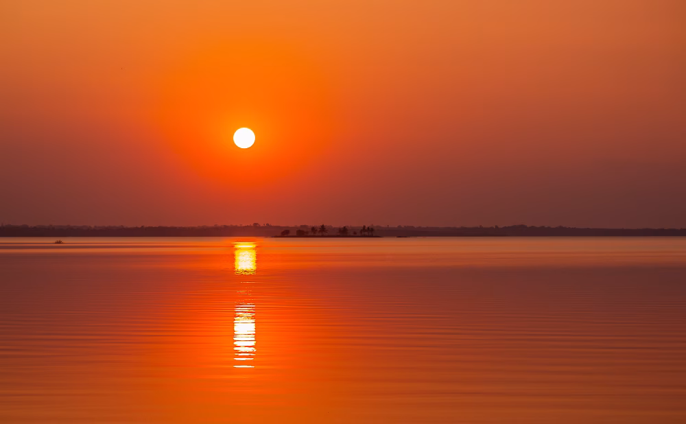 Serene Sunset Over a Calm Lake Reflecting Orange and Golden Colors