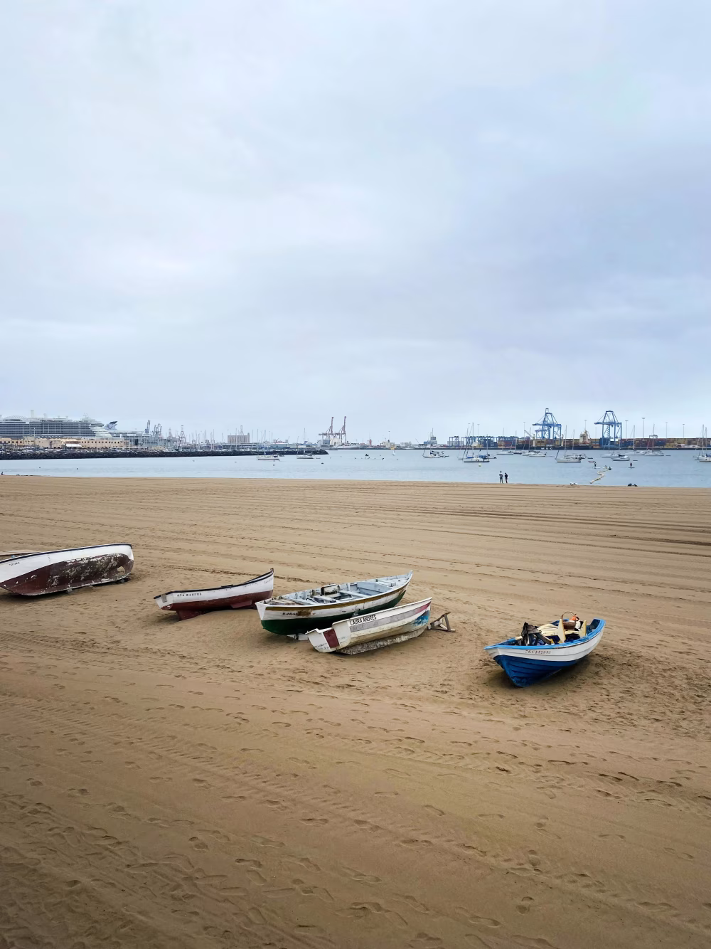 Small Boats Resting on Sandy Beach Beside a Tranquil Ocean Harbor
