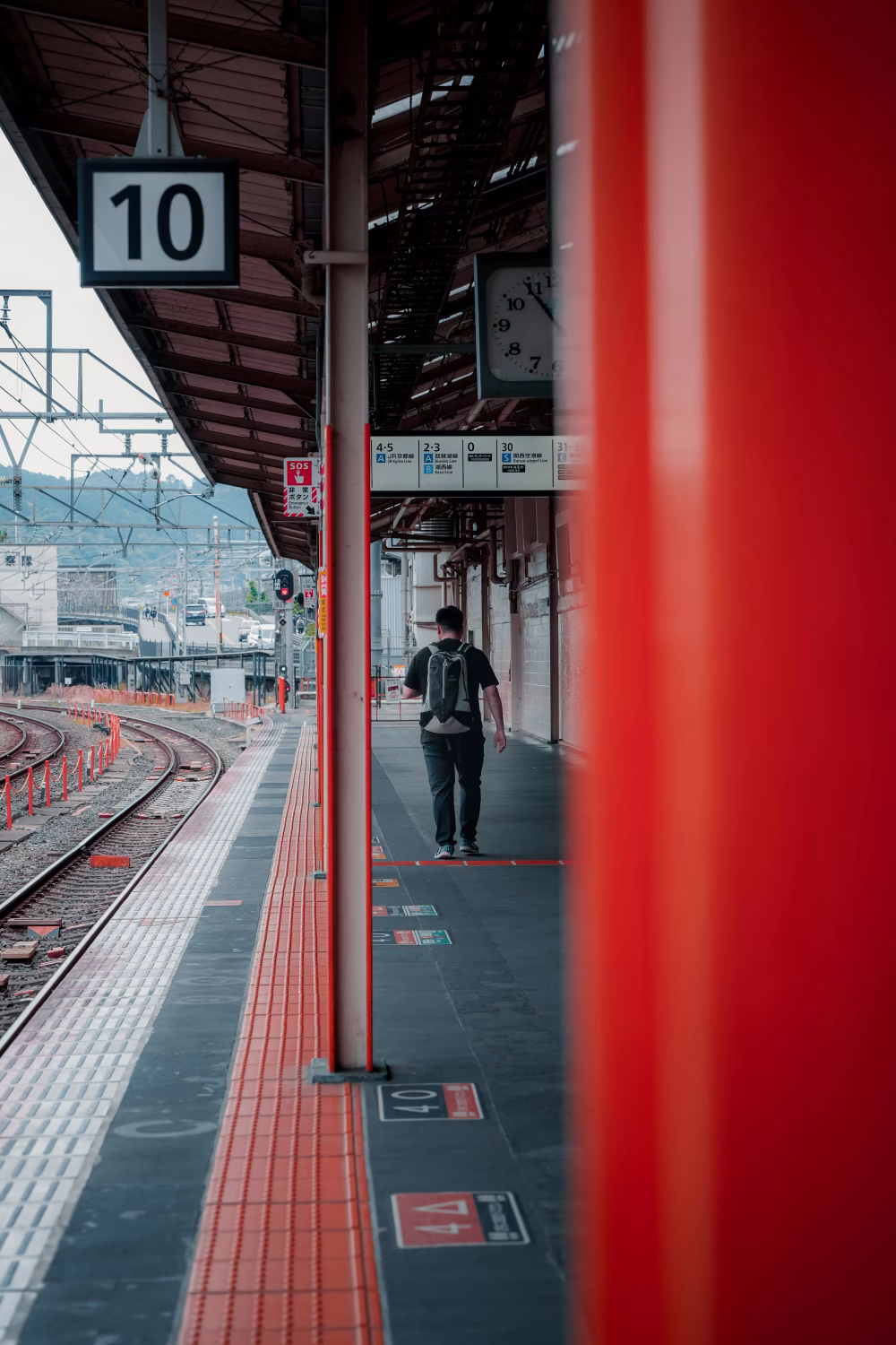 Traveler Walking Along Platform at Train Station With Vibrant Red Accents