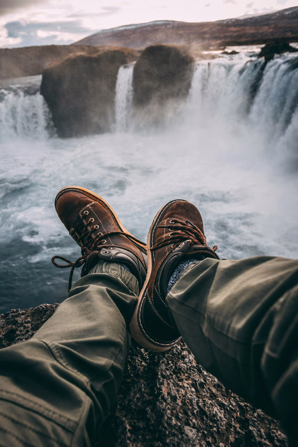 Traveler's Boots Dangling Above a Scenic Waterfall in Stunning Wilderness