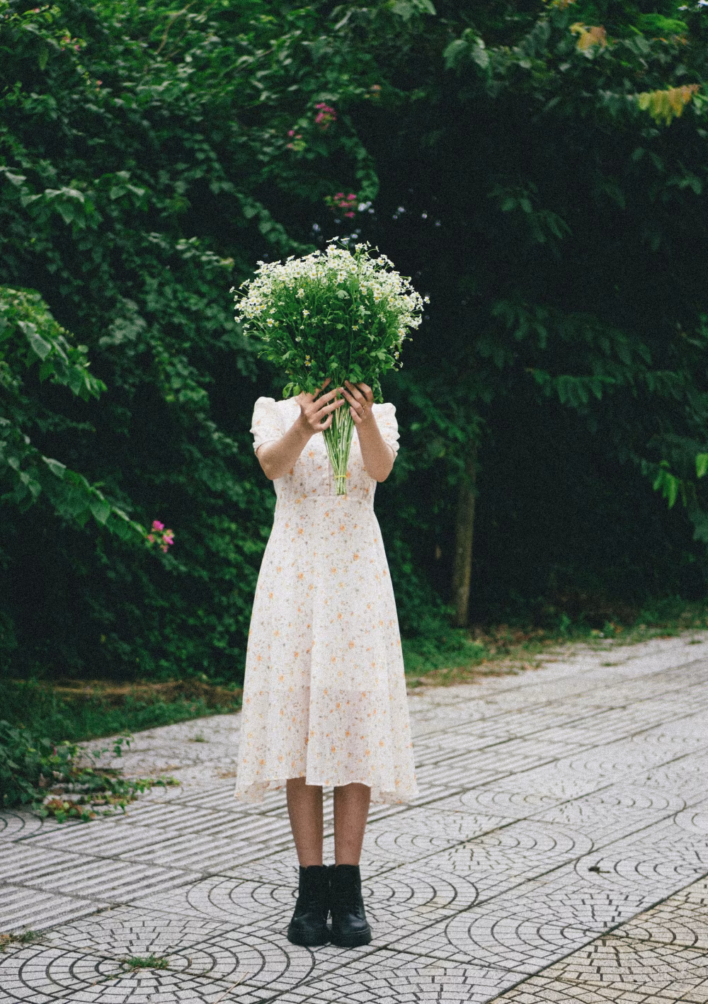Woman Holding Flowers in Garden Wearing Rustic Dress with Greenery Background