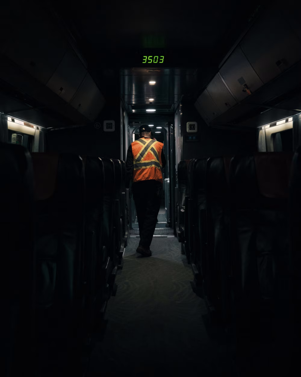 Worker Walking Through a Quiet Train Compartment During the Night