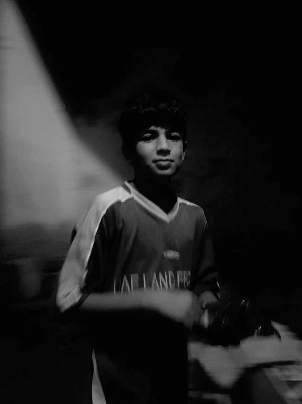 Young Boy in Sports Jersey Stands in Low Light Portrait, Reflective and Calm Mood