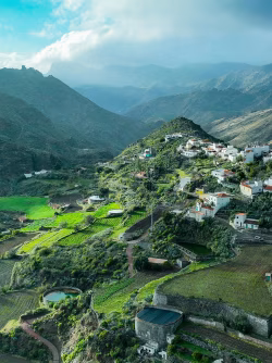 Aerial View of Mountain Village Surrounded by Lush Green Fields and Hills