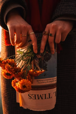 Close-Up of Hands Holding Flowers with Rings and Newspaper