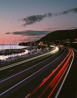 Coastal Highway With Light Trails and Serene Marina at Dusk