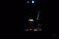 Dark Still Life Featuring Whiskey Bottle, Glass, and Rising Smoke