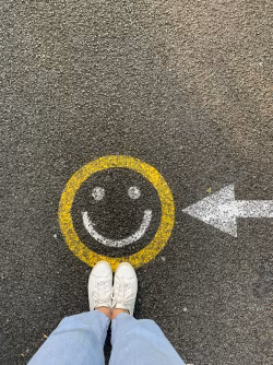 Feet Near a Ground Smiley Face with Arrow Sign Directions