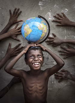 Happy Child Holding Globe Surrounded by Hands Embracing Unity