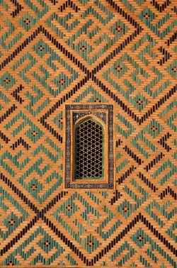 Ornate Geometric Mosaic Wall with a Decorative Window in a Historic Building