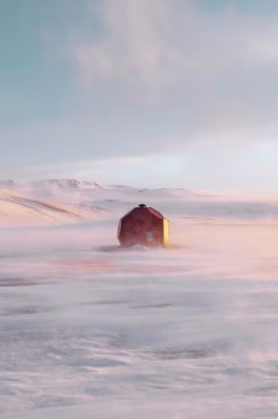 Remote Winter Cabin Amidst Snow-Covered Landscape in Soft Sunset Light