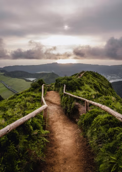 Scenic Sunset Over Green Hills Along Nature Path With Wooden Fence