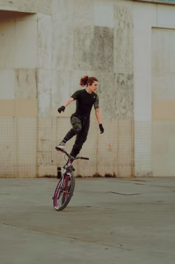 Skilled BMX Rider Performs Balance Trick On Street Near Industrial Concrete Wall