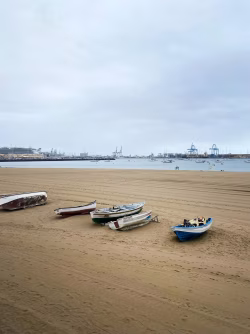Small Boats Resting on Sandy Beach Beside a Tranquil Ocean Harbor
