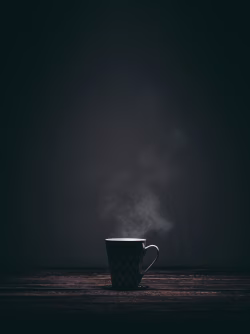 Steaming Cup of Coffee on a Wooden Table in Dim Light Setting