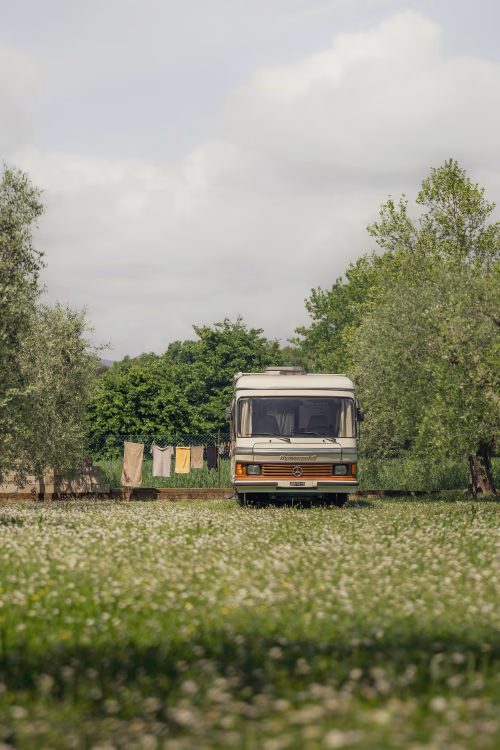 Beautiful Retro Camper in a Green Meadow with Clothes Hanging Outdoors