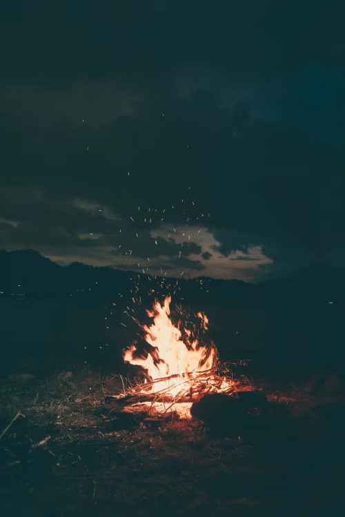 Burning Campfire Under a Dark Night Sky with Glowing Embers