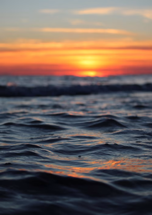 Calm Ocean Waves at Sunset with Vibrant Orange and Yellow Sky