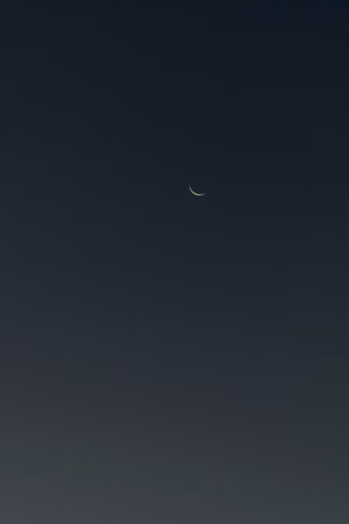Crescent Moon in the Night Sky with Minimal Stars Visible
