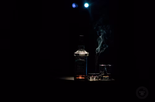 Dark Still Life Featuring Whiskey Bottle, Glass, and Rising Smoke