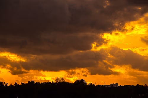 Dramatic Sunset Over Silhouetted Horizon With Dark Clouds and Golden Light