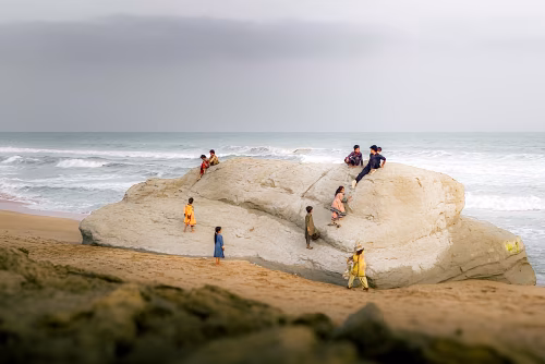 Families and Friends Enjoying a Day on a Large Rock by the Beach and Ocean