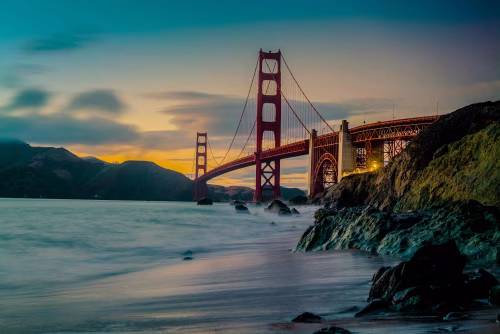 Golden Gate Bridge at Sunset Amid Serene Waters and Rocky Shores