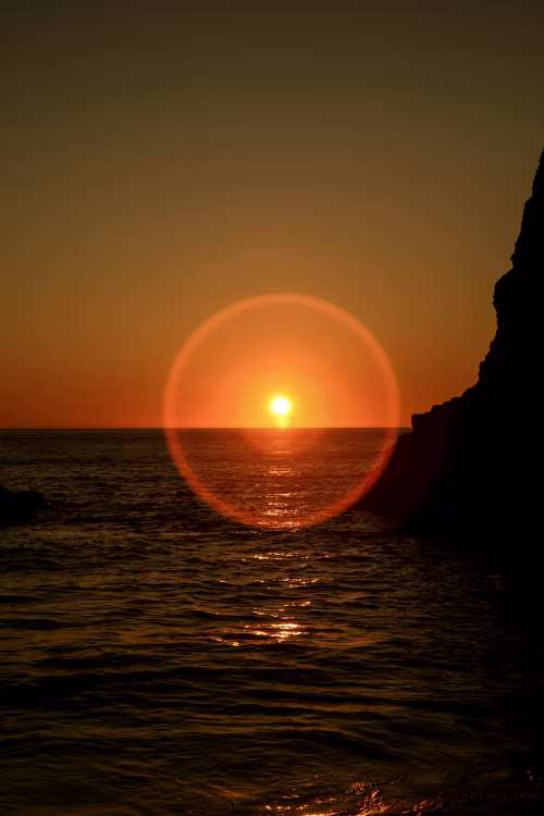 Golden Sunset Over Ocean With Vibrant Lens Flare Near Cliff Edge