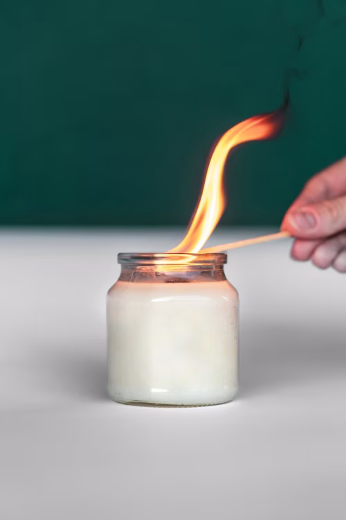 Hand Lighting a Candle in a Jar with a Matchstick
