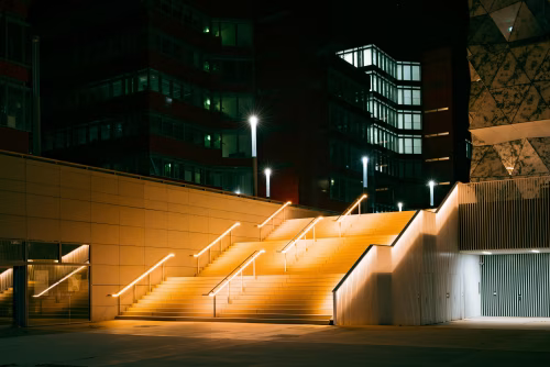 Illuminated Staircase and Urban Buildings at Night with Modern Architecture