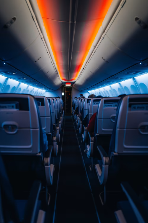 A captivating view of an airplane interior featuring empty passenger seats and ambient lighting, creating a serene travel atmosphere.