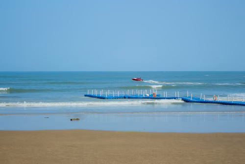 Peaceful Beach Scene with Pier and Boat Over Calm Ocean Waters