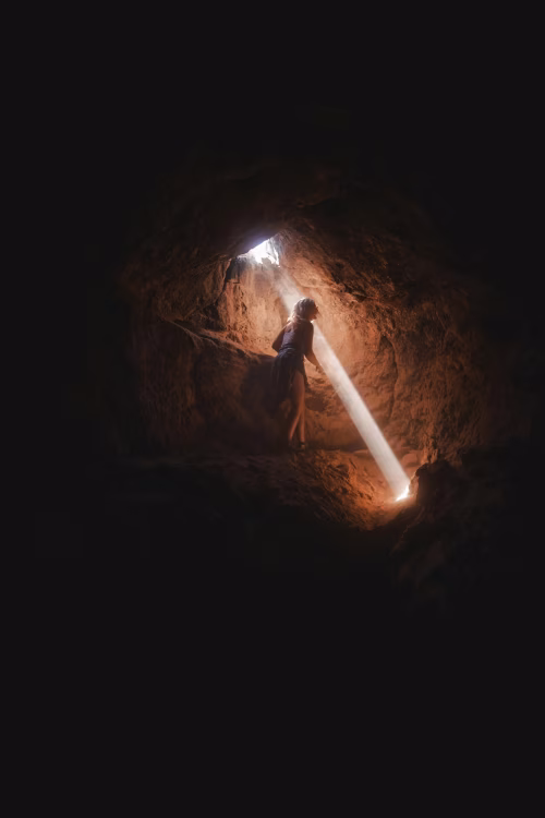 Person Standing in a Cave Illuminated by a Ray of Sunlight