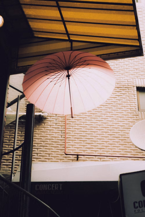 Pink Umbrella Suspended Beneath Urban Architecture with Light and Textures