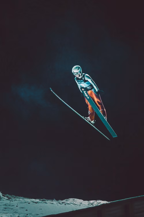 Professional Ski Jumper Soaring Through the Night Sky Mid-Jump