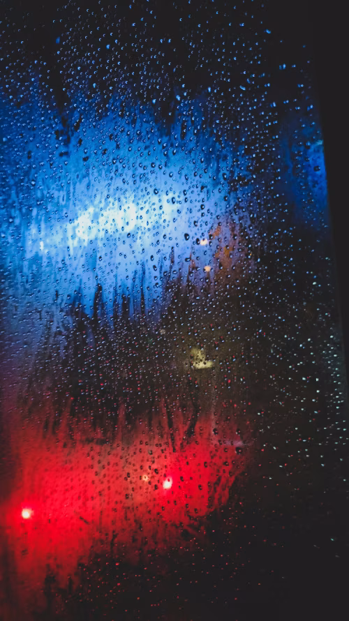 Rain Drops on Window Illuminated by Red and Blue Night Lights