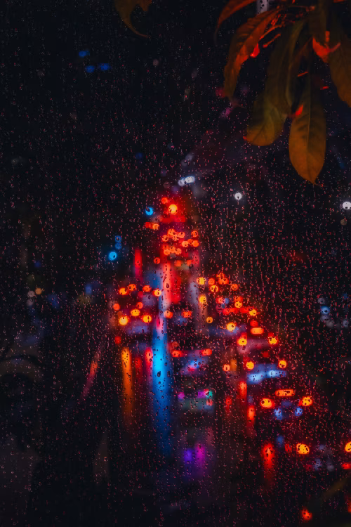 Raindrops on Glass Overlooking City Traffic Lights at Night