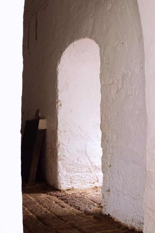 Rustic Arched Doorway in Sunlit Stone Structure with Textured Walls