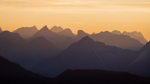 Scenic Mountain Range Silhouettes at Sunset with Warm Vibrant Sky