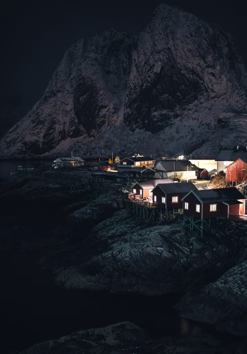 Scenic Nordic Village at Night Amidst Snowy Mountains and Ocean